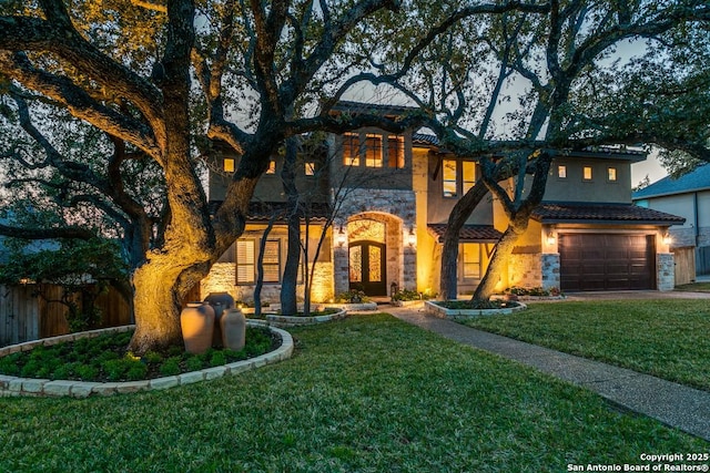 view of front of house with an attached garage, fence, stone siding, stucco siding, and a front lawn