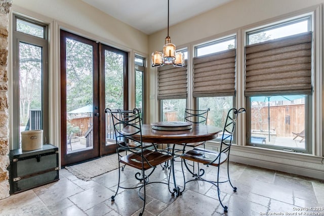 dining space with french doors, stone tile flooring, and an inviting chandelier