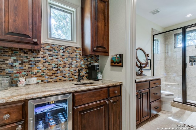 interior space with visible vents, decorative backsplash, a sink, beverage cooler, and bar