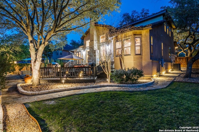 exterior space with a yard, a wooden deck, fence, and stucco siding