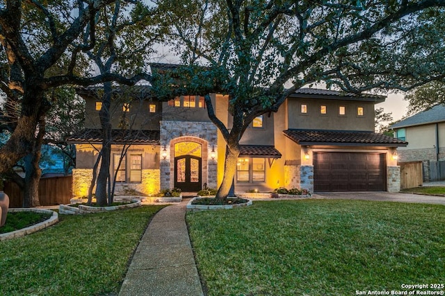 mediterranean / spanish-style home with driveway, stone siding, fence, and a yard