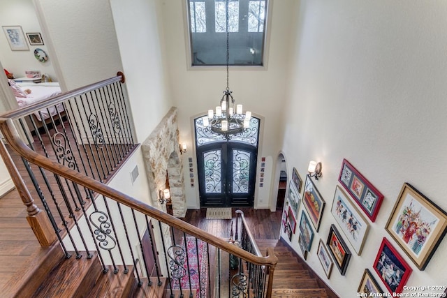 foyer featuring a chandelier, arched walkways, a towering ceiling, french doors, and dark wood finished floors