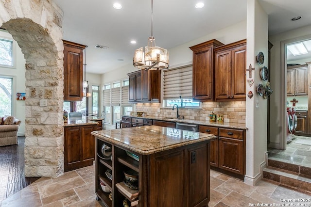 kitchen with stone tile floors, washing machine and dryer, visible vents, and a center island