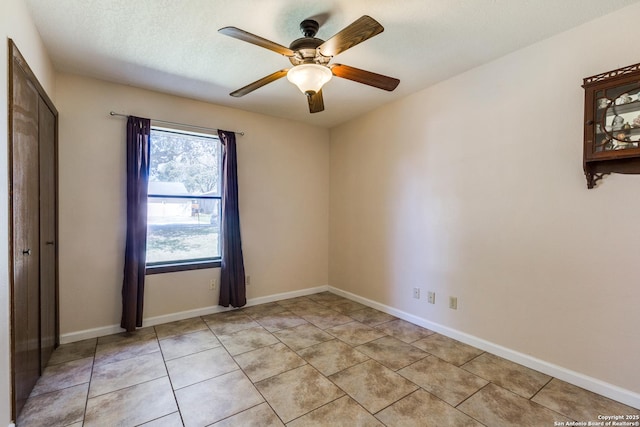 unfurnished room featuring light tile patterned floors, ceiling fan, baseboards, and a textured ceiling