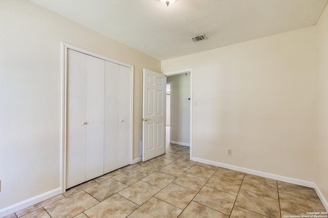 unfurnished bedroom featuring a closet, visible vents, baseboards, and light tile patterned floors