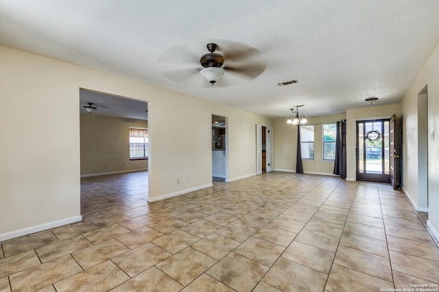 spare room featuring light tile patterned floors, baseboards, visible vents, and ceiling fan with notable chandelier