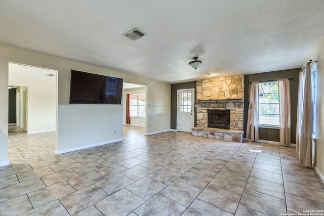 unfurnished living room with a wealth of natural light, visible vents, a fireplace, and light tile patterned flooring