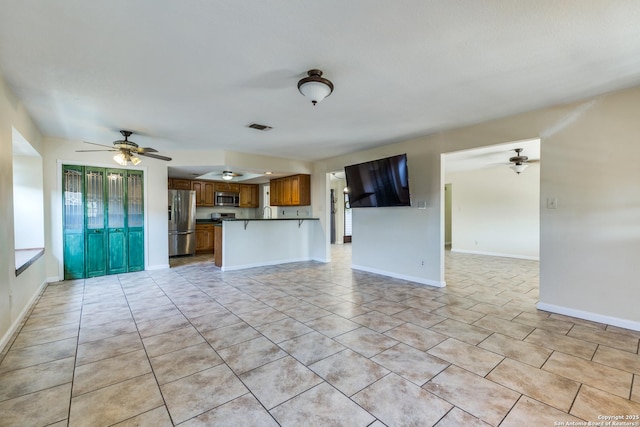 unfurnished living room with baseboards, visible vents, and a ceiling fan