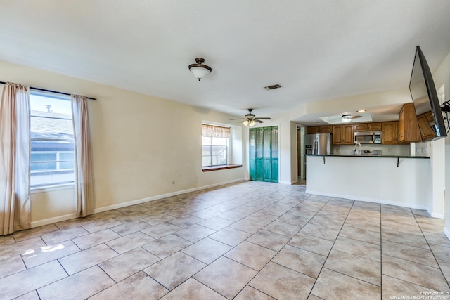 unfurnished living room with ceiling fan, light tile patterned floors, visible vents, and baseboards