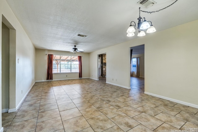 empty room featuring light tile patterned floors, visible vents, a textured ceiling, and ceiling fan with notable chandelier