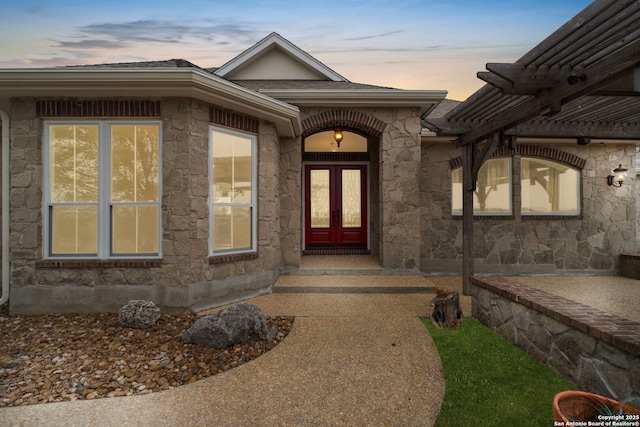 exterior entry at dusk with stone siding and french doors