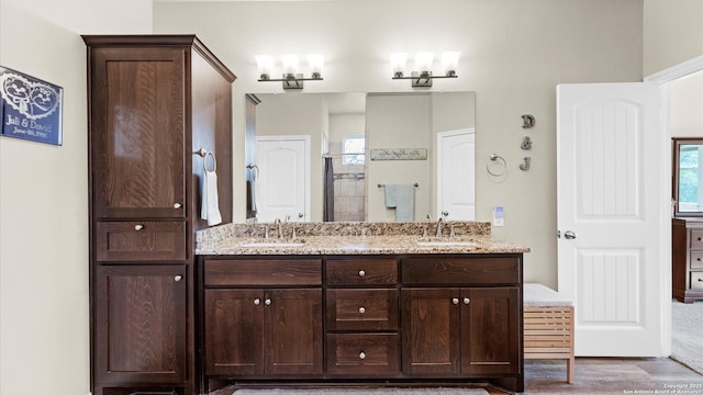 full bath with double vanity, a stall shower, and a sink