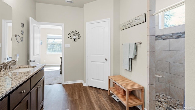 bathroom with a walk in shower, wood finished floors, vanity, visible vents, and baseboards