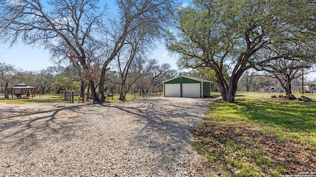 exterior space featuring a garage, a gazebo, and an outbuilding