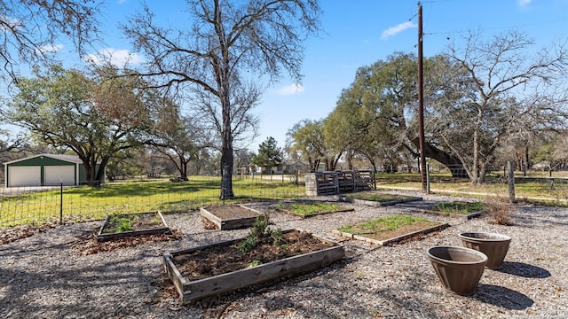 view of yard featuring a detached garage, fence, and an outbuilding