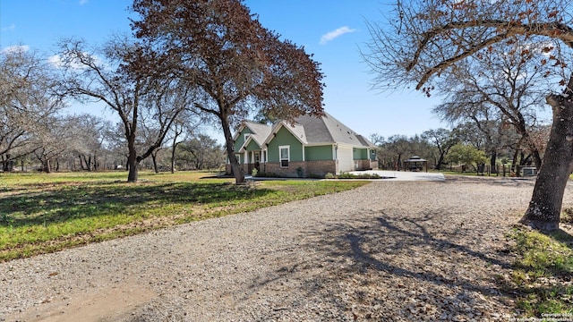 view of side of property with gravel driveway and a lawn