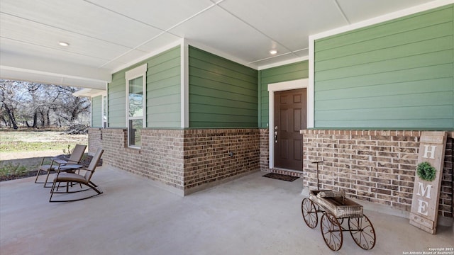 entrance to property featuring covered porch and brick siding