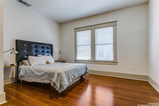 bedroom featuring dark wood finished floors, visible vents, and baseboards