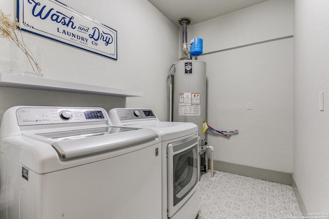 clothes washing area featuring laundry area, washing machine and dryer, water heater, and baseboards