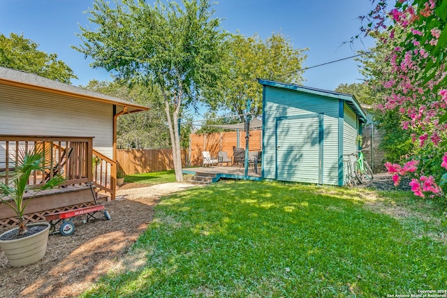 view of yard with a shed, a deck, a fenced backyard, and an outbuilding