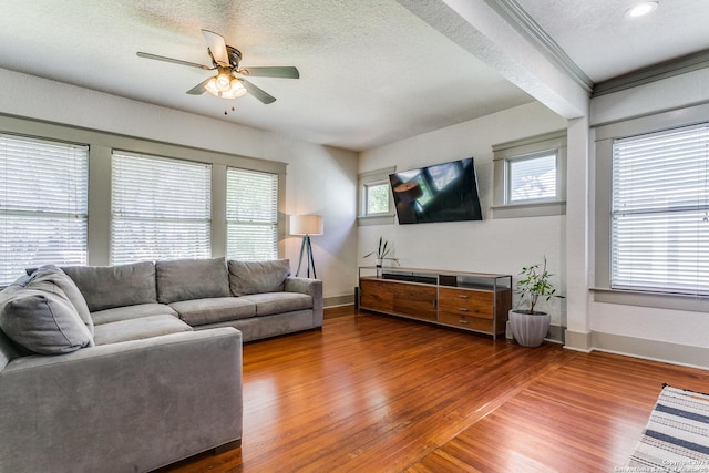 living area with a ceiling fan, a textured ceiling, baseboards, and wood finished floors