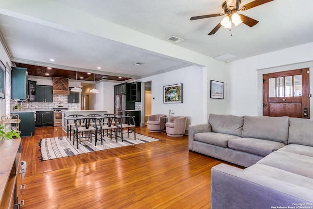 living area with ceiling fan, a textured ceiling, recessed lighting, dark wood-style flooring, and visible vents