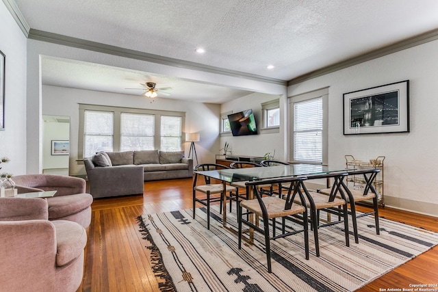 dining space with crown molding, hardwood / wood-style floors, a ceiling fan, a textured ceiling, and baseboards