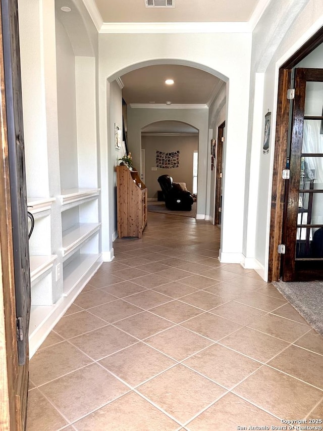 corridor featuring light tile patterned floors, baseboards, visible vents, and crown molding