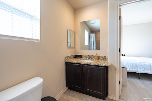 ensuite bathroom with visible vents, baseboards, toilet, ensuite bath, and vanity