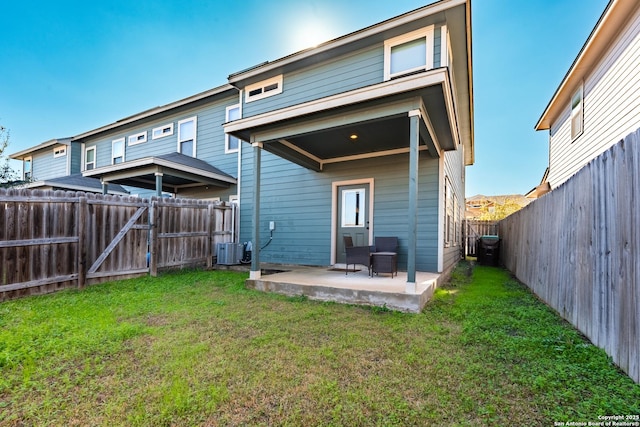 back of property with a patio, a lawn, a gate, central AC, and a fenced backyard