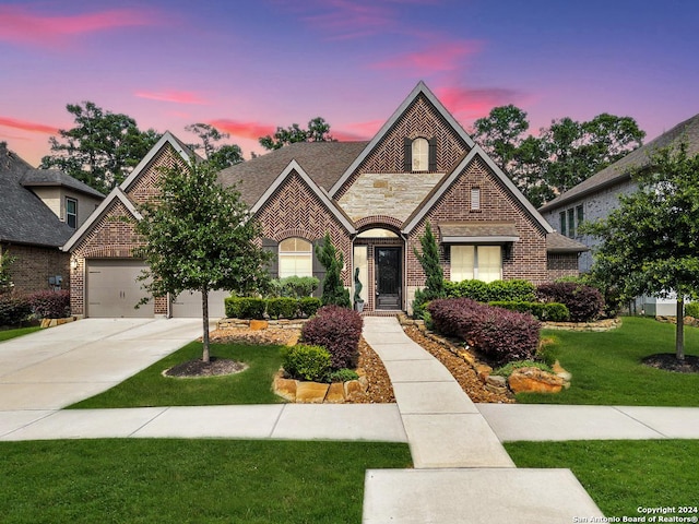 view of front of house featuring brick siding, a shingled roof, a lawn, stone siding, and driveway