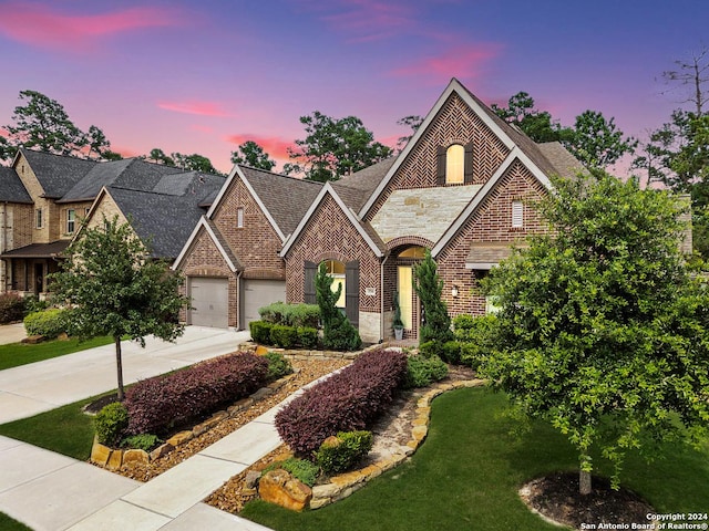 view of front of home featuring a garage, brick siding, concrete driveway, stone siding, and a lawn