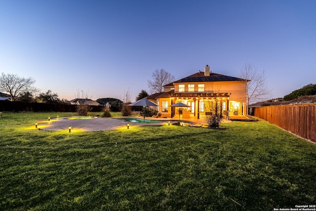 back of property at dusk with a fenced in pool, a yard, a patio, a chimney, and a fenced backyard