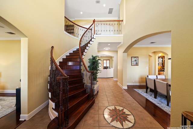 entryway with baseboards, visible vents, crown molding, and tile patterned floors