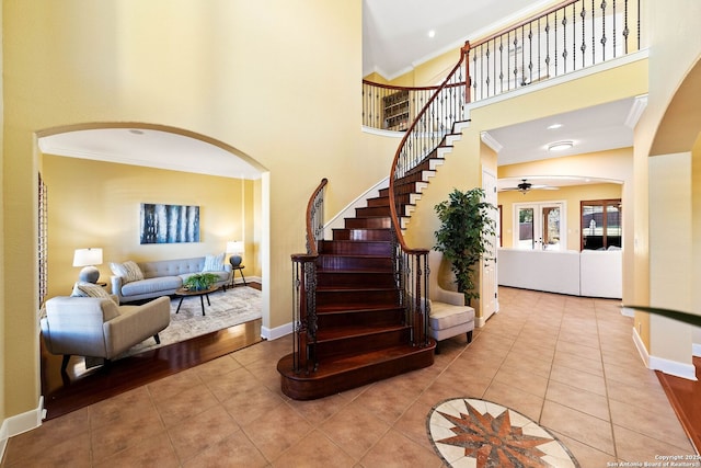 foyer entrance with a high ceiling, light tile patterned flooring, crown molding, and baseboards