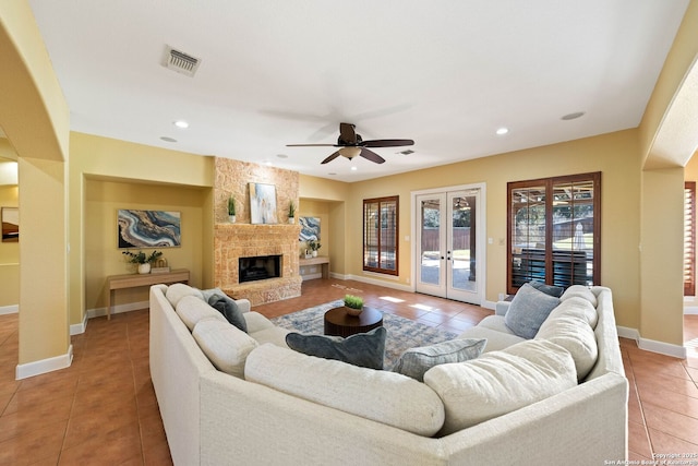 living area with visible vents, light tile patterned flooring, french doors, and a stone fireplace