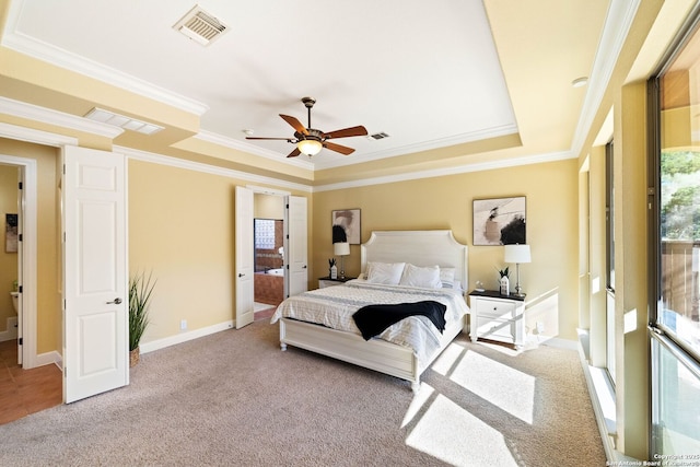 bedroom featuring light colored carpet, a tray ceiling, visible vents, and crown molding