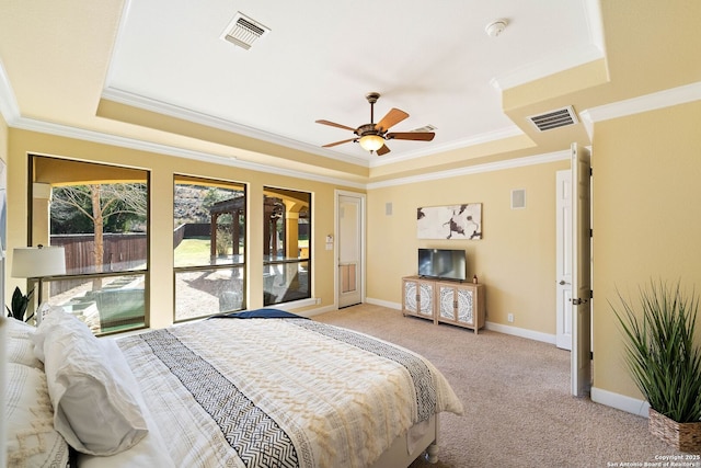 bedroom with light carpet, visible vents, and a tray ceiling