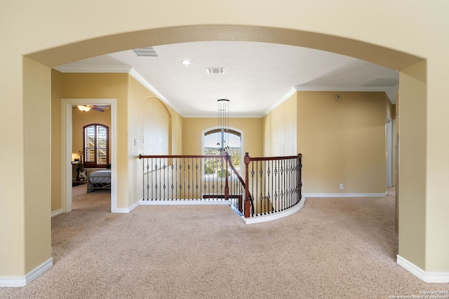 hall with arched walkways, plenty of natural light, and light colored carpet