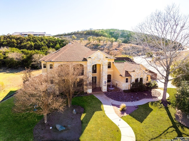 view of front of property featuring a front yard, stone siding, and stucco siding