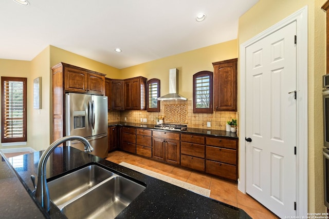 kitchen with a sink, appliances with stainless steel finishes, wall chimney range hood, and tasteful backsplash