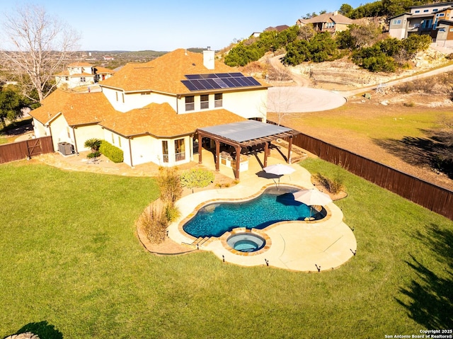 exterior space with a fenced in pool, solar panels, a lawn, an in ground hot tub, and a fenced backyard