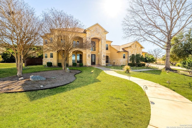 mediterranean / spanish-style house featuring stone siding, fence, stucco siding, and a front yard