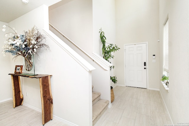 entryway with baseboards, stairway, and a high ceiling