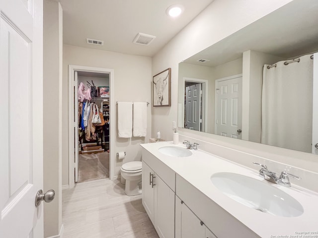 full bathroom with visible vents, a sink, a spacious closet, and double vanity