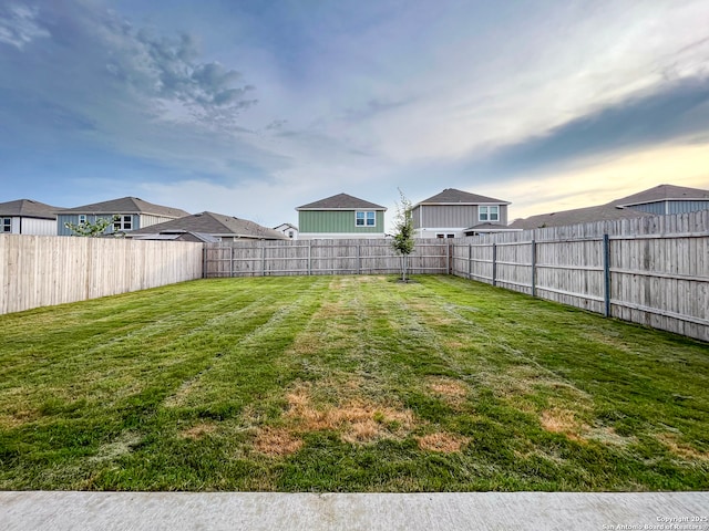 yard at dusk featuring a fenced backyard