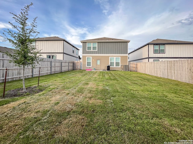 rear view of house with a yard, board and batten siding, and a fenced backyard