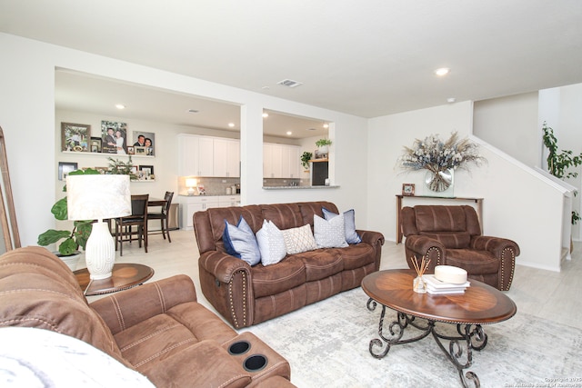 living room featuring light wood-type flooring, visible vents, and recessed lighting