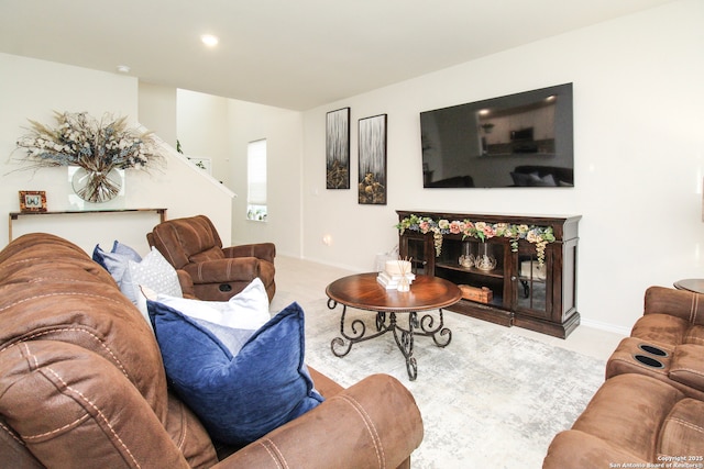 living room with a glass covered fireplace, light colored carpet, and baseboards