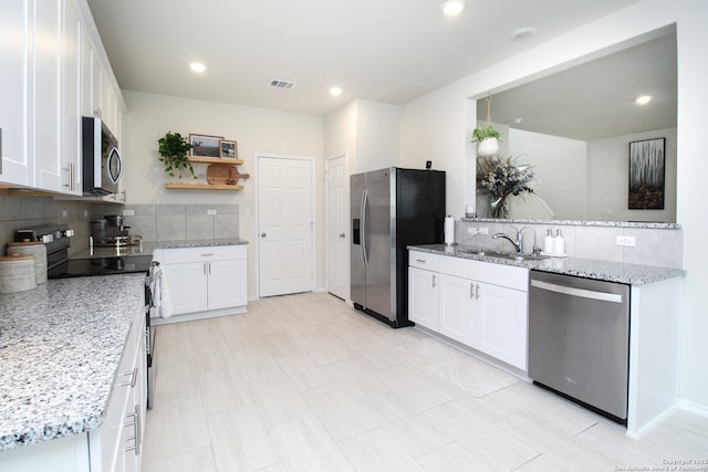 kitchen with stainless steel appliances, white cabinets, a sink, and light stone counters